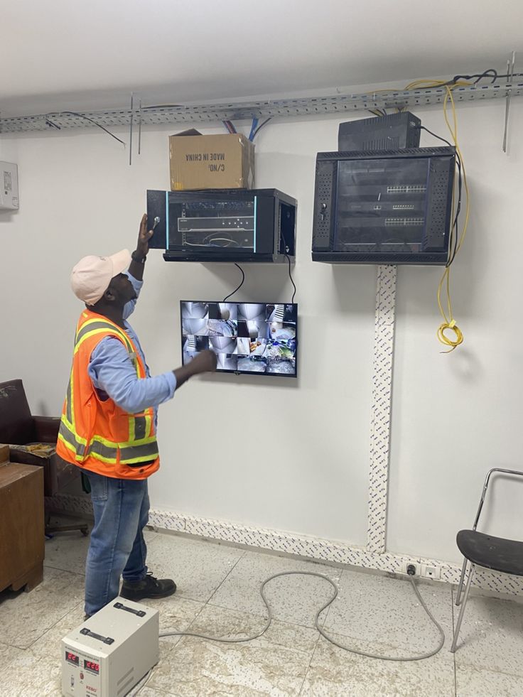 Bytecraft technician commissioning wall-mounted CCTV racks and a live monitor setup at a commercial site in Lusaka