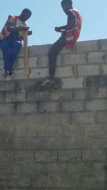 Technicians installing perimeter security equipment on a boundary wall in Lusaka